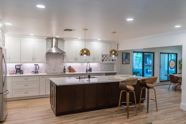 kitchen featuring pendant lighting, white cabinets, and wall chimney exhaust hood