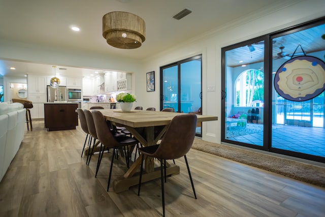 dining space featuring ornamental molding and light hardwood / wood-style flooring