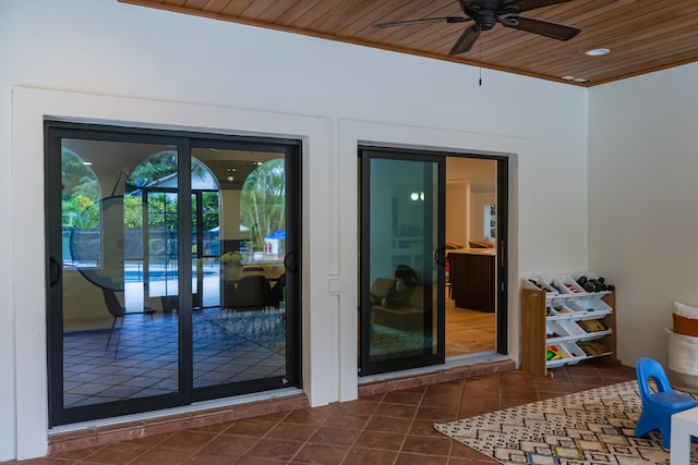 doorway to outside with ceiling fan, wood ceiling, and dark tile patterned floors