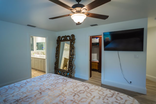 unfurnished bedroom featuring ceiling fan, ensuite bath, and light hardwood / wood-style flooring