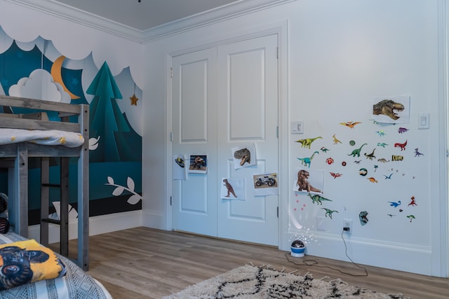 bedroom with crown molding, light hardwood / wood-style floors, and a closet