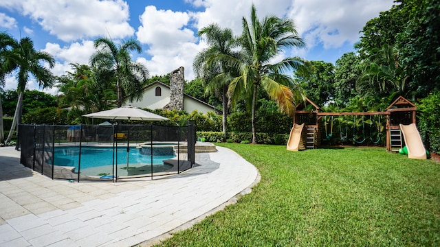 view of pool featuring a lawn, a patio, and a playground