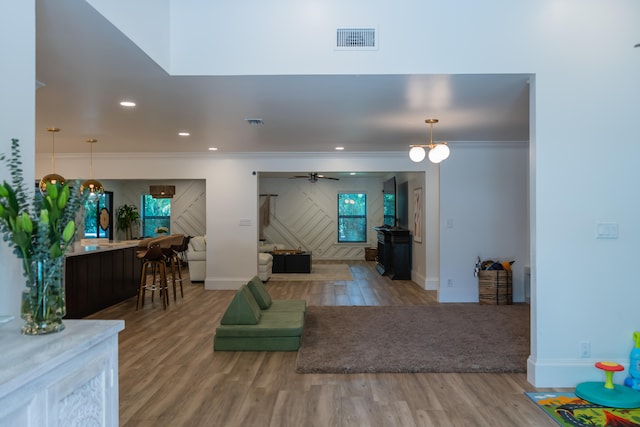 living room with ceiling fan, ornamental molding, and light hardwood / wood-style flooring