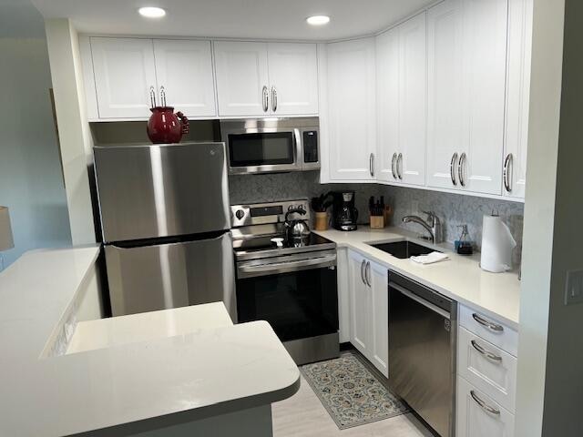 kitchen featuring appliances with stainless steel finishes, sink, tasteful backsplash, and white cabinets