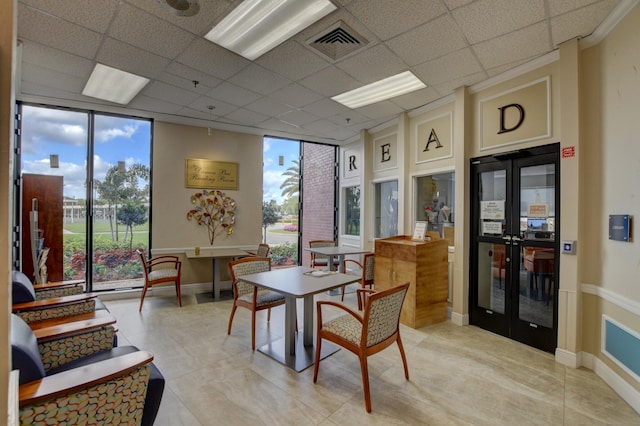 tiled dining space featuring a drop ceiling and expansive windows