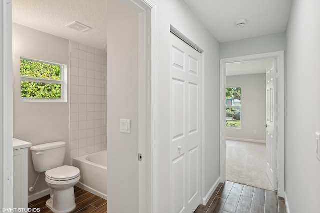 full bathroom featuring a wealth of natural light, toilet, tiled shower / bath combo, and vanity