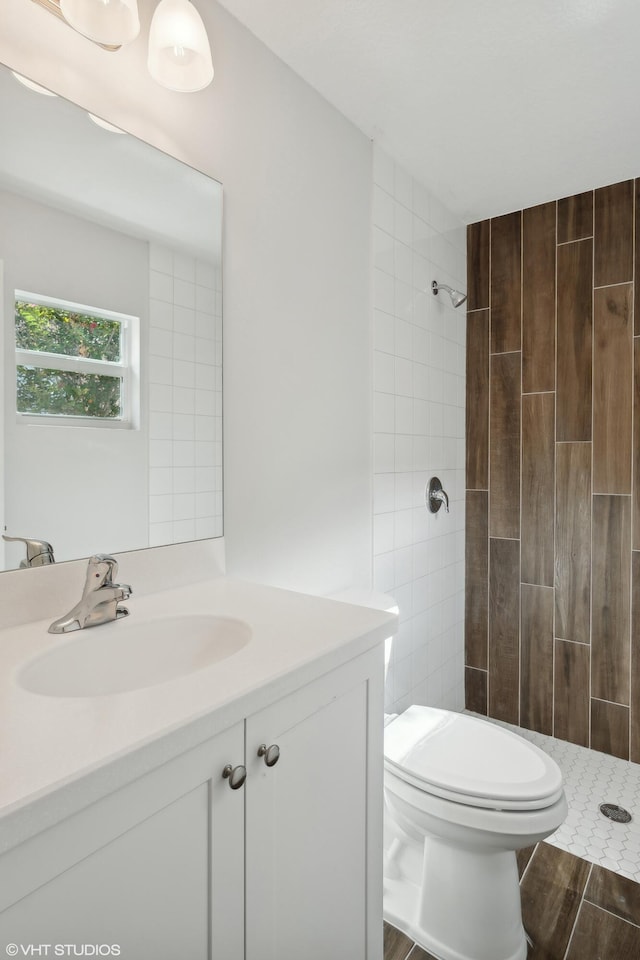 bathroom with vanity, tiled shower, and toilet