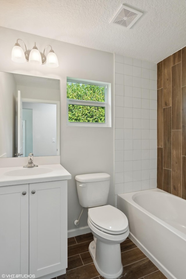 full bathroom with a textured ceiling, vanity, bathing tub / shower combination, and toilet