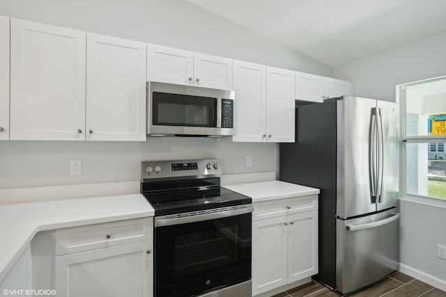 kitchen with white cabinetry, appliances with stainless steel finishes, and lofted ceiling