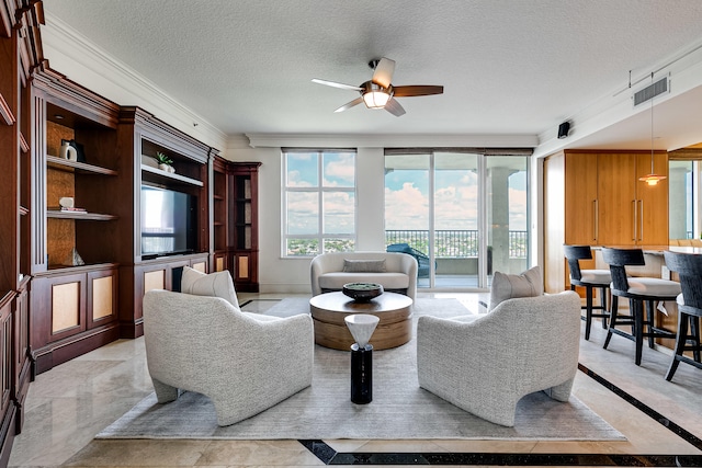 living room featuring ceiling fan, light tile patterned floors, crown molding, and a textured ceiling