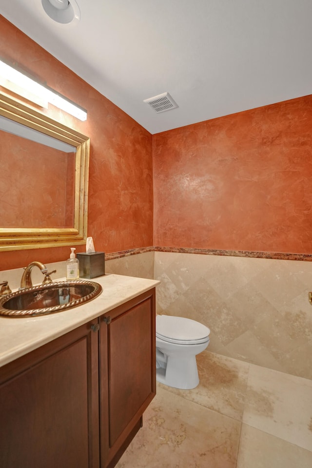 bathroom with tile walls, tile patterned floors, vanity, and toilet