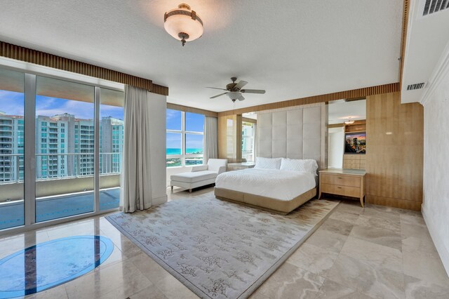 unfurnished bedroom featuring ceiling fan, access to outside, light tile patterned floors, and a water view