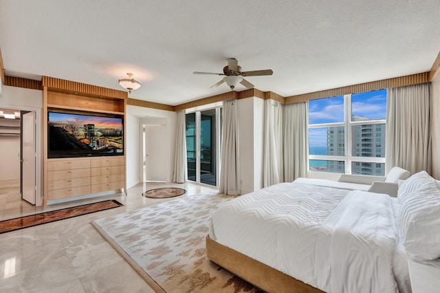 tiled bedroom with ceiling fan, access to outside, a textured ceiling, and a water view