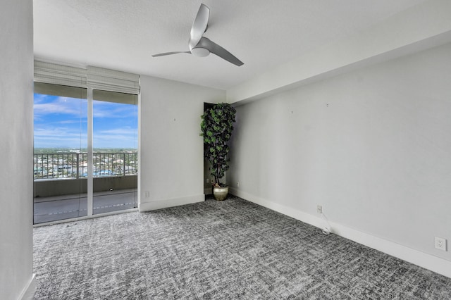 spare room with ceiling fan, carpet, a wall of windows, and a textured ceiling