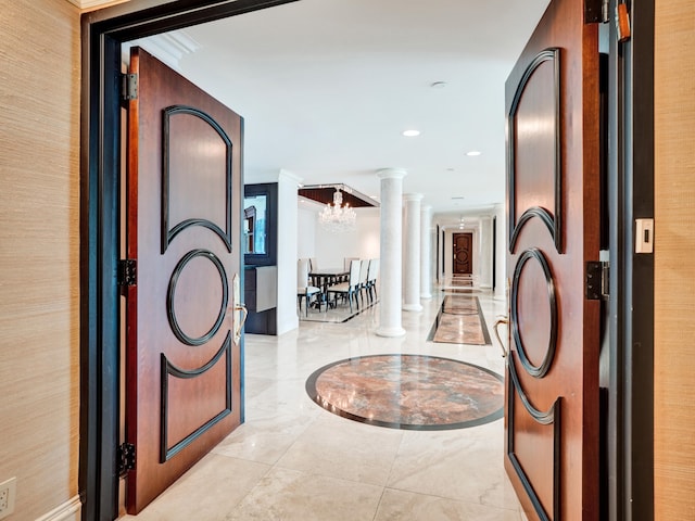 hallway with a notable chandelier, recessed lighting, marble finish floor, ornamental molding, and ornate columns