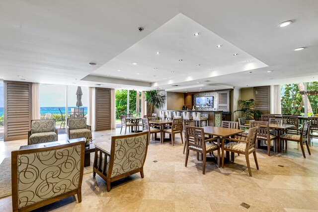 tiled dining room with a raised ceiling and a water view