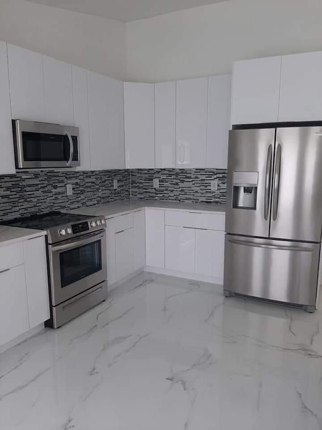 kitchen featuring white cabinets, backsplash, and appliances with stainless steel finishes