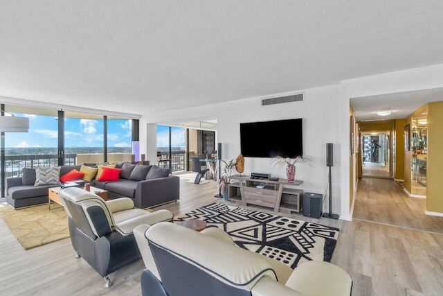 living room featuring a textured ceiling, light wood-type flooring, and expansive windows