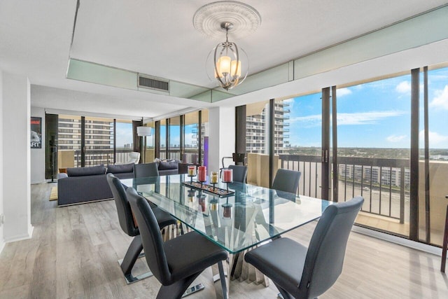 dining space with a wall of windows, a chandelier, and light hardwood / wood-style floors