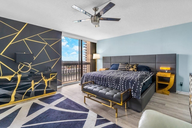 bedroom featuring a textured ceiling, access to outside, ceiling fan, light hardwood / wood-style floors, and floor to ceiling windows