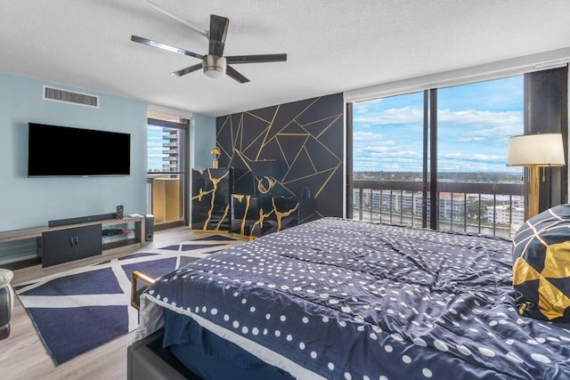 bedroom with ceiling fan, a textured ceiling, multiple windows, and hardwood / wood-style flooring