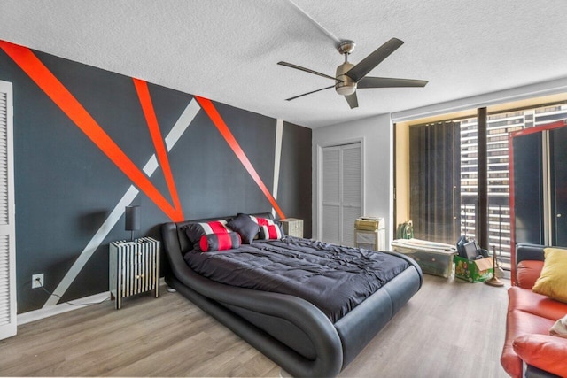 bedroom with a textured ceiling, radiator, hardwood / wood-style flooring, a closet, and ceiling fan