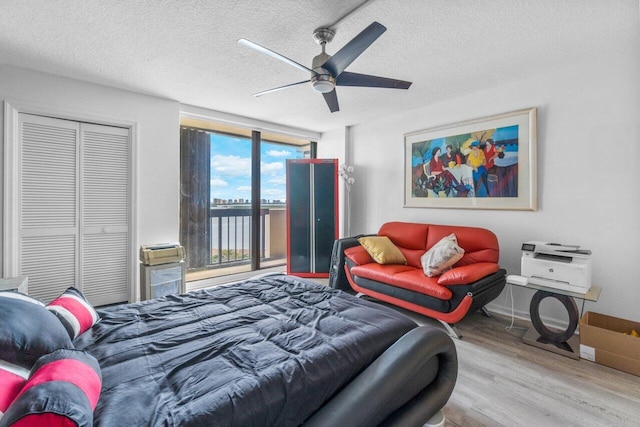 bedroom featuring a textured ceiling, light hardwood / wood-style floors, a closet, ceiling fan, and access to exterior