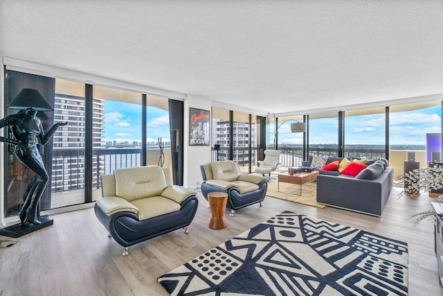 living room featuring a wall of windows, light wood-type flooring, and a textured ceiling