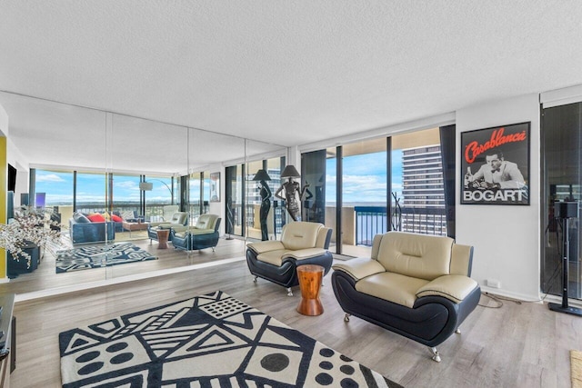 living room with a textured ceiling, floor to ceiling windows, and light hardwood / wood-style floors