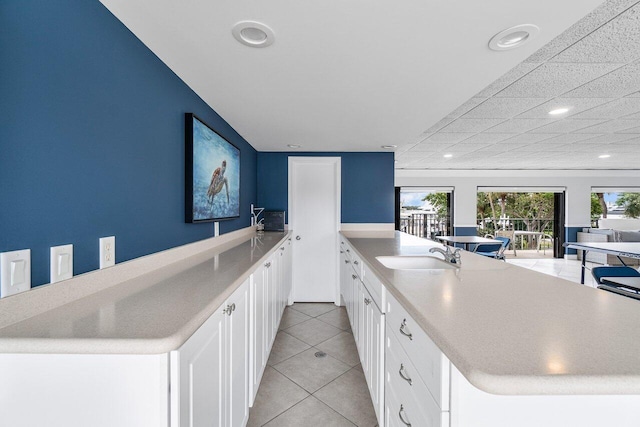 kitchen featuring light tile patterned floors, sink, and white cabinetry