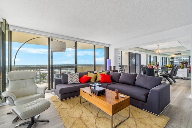 living room featuring a healthy amount of sunlight, a textured ceiling, a notable chandelier, and light hardwood / wood-style floors