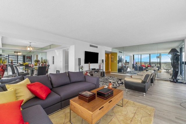 living room featuring light hardwood / wood-style flooring, a textured ceiling, and an inviting chandelier