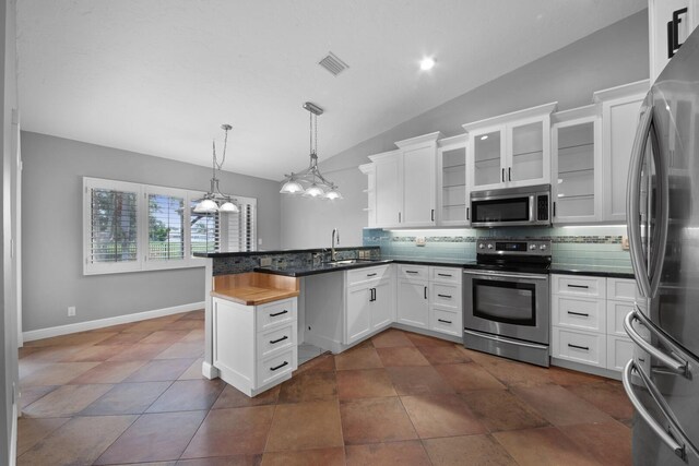 kitchen featuring appliances with stainless steel finishes, dark tile patterned flooring, kitchen peninsula, and backsplash