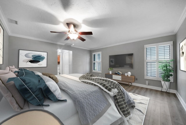 bedroom with ceiling fan, hardwood / wood-style floors, ornamental molding, and multiple windows