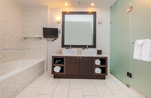 bathroom featuring tile patterned floors, double sink vanity, and a relaxing tiled tub