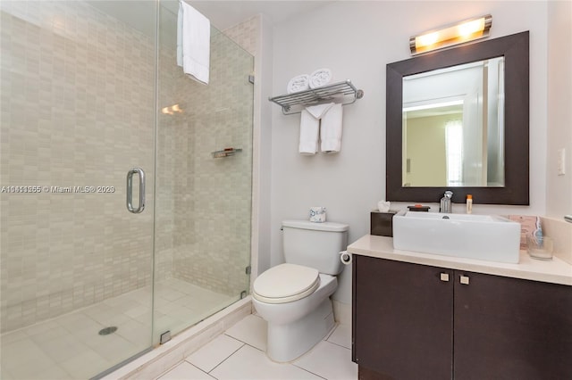 bathroom with a shower with shower door, vanity, toilet, and tile patterned flooring