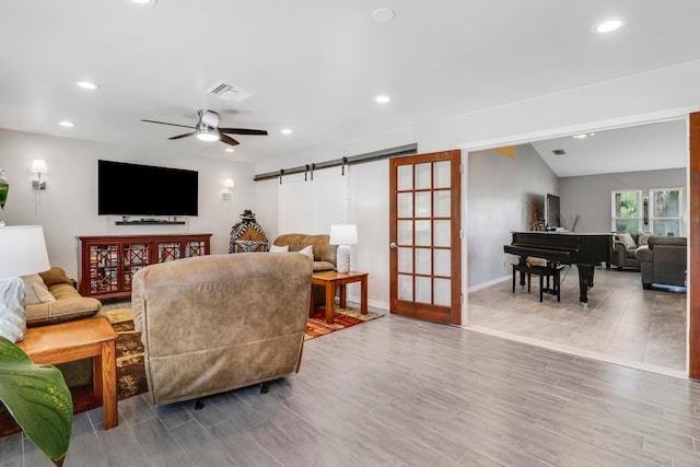 living room with ceiling fan, vaulted ceiling, a barn door, and hardwood / wood-style floors