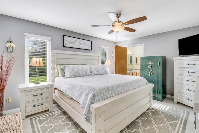 bedroom featuring ceiling fan, ensuite bathroom, and multiple windows