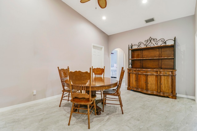 tiled dining space with ceiling fan and high vaulted ceiling