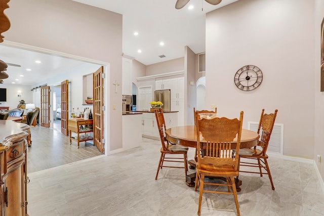 dining room with ceiling fan, a high ceiling, and light tile patterned floors