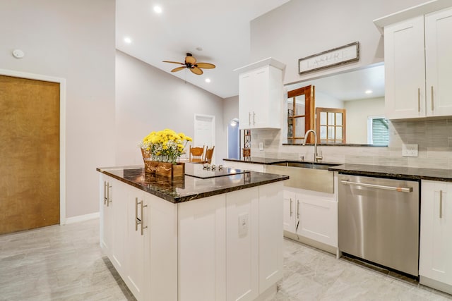 kitchen with ceiling fan, dark stone counters, stainless steel dishwasher, a kitchen island, and tasteful backsplash