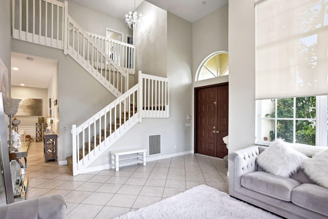 tiled foyer entrance featuring a towering ceiling and a chandelier