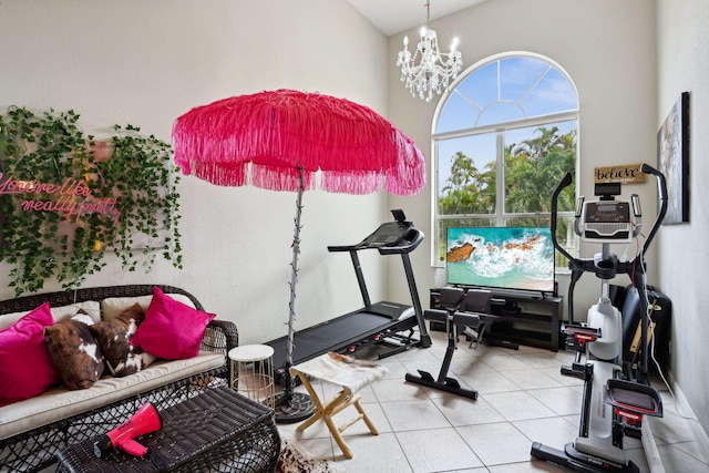 exercise area featuring light tile patterned flooring, a high ceiling, and a chandelier