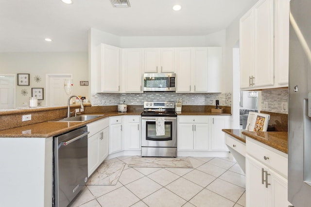 kitchen featuring appliances with stainless steel finishes, backsplash, sink, white cabinets, and light tile patterned floors