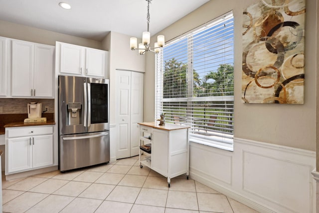 kitchen with light tile patterned flooring, a wealth of natural light, stainless steel fridge, and backsplash