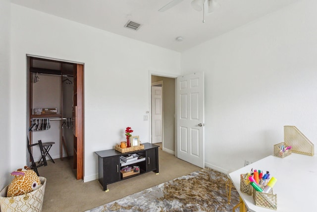 bedroom with ceiling fan, light colored carpet, a closet, and a walk in closet