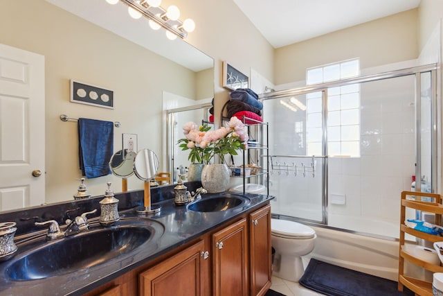 full bathroom with toilet, tile patterned flooring, double vanity, and bath / shower combo with glass door