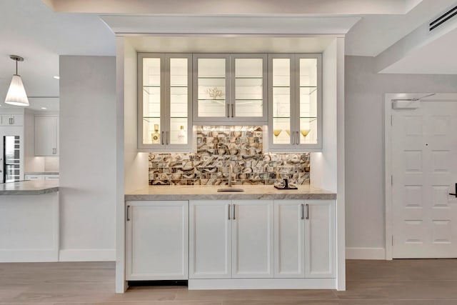 bar with white cabinetry, a wealth of natural light, tasteful backsplash, and pendant lighting