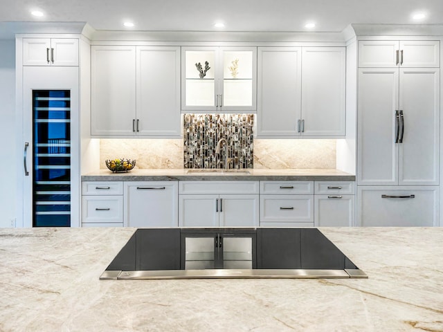 kitchen with backsplash, white cabinetry, and sink