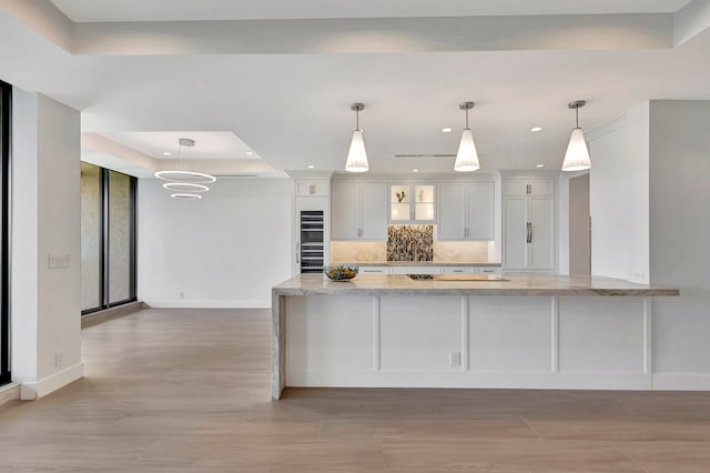 kitchen with backsplash, light stone countertops, white cabinetry, a raised ceiling, and black appliances